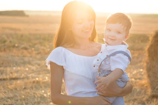 Madre che abbraccia il suo bambino durante una passeggiata nel parco al tramonto — Foto Stock