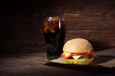 Ev yapımı burger ve ahşap arka planda soğuk içecek kola.