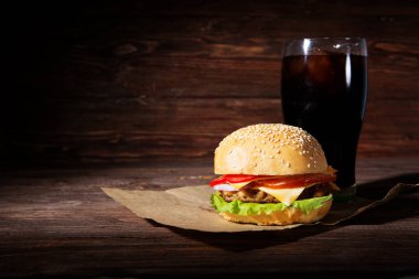 Ev yapımı burger ve ahşap arka planda soğuk içecek kola.