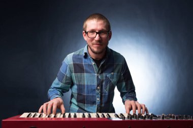 Klavye sentezleyici piyano tuşlarında çalan sanatçı. Erkek müzisyen bir müzik aleti çalıyor.