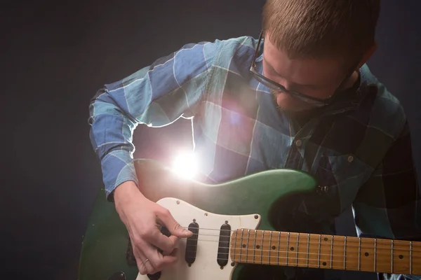 Mladý kytarista hraje na elektrickou kytaru přes tmavé pozadí — Stock fotografie