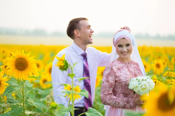 Lachend jong islamitisch paar portret op zonnebloemen veld — Stockfoto