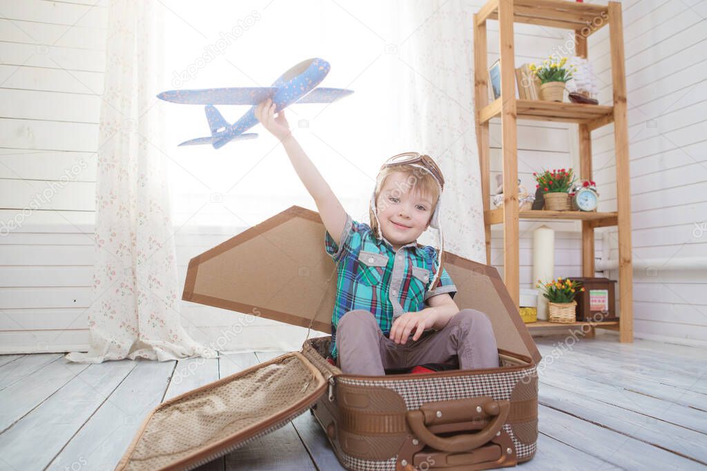 Children boy wearing pilot costume making ready to fly gesture standing on living room wooden floor at home