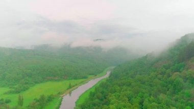 Bulutların, dağların, ormanın ve nehrin havadan çekilmiş videosu.