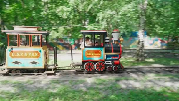 Mamá y los niños montan en una pequeña locomotora de vapor. Diversión familiar en el parque de atracciones — Vídeos de Stock