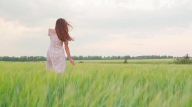 Buğday tarlasında gün batımında beyaz elbiseli bir kız.