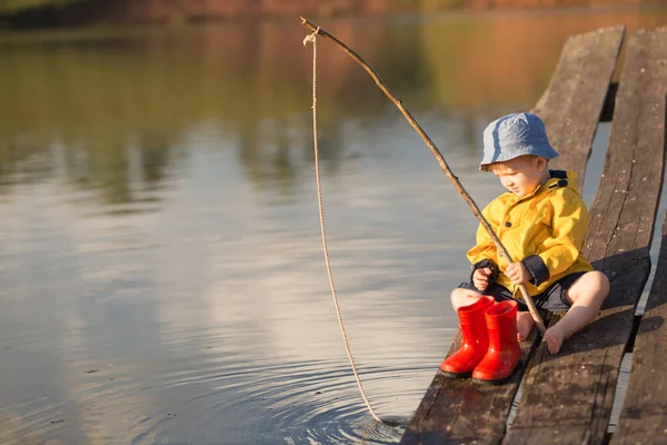 Kleine jongen vangt een vis uit houten steiger — Stockfoto