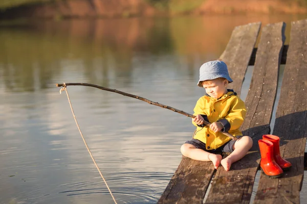 Kleiner Junge fängt einen Fisch vom Holzsteg — Stockfoto