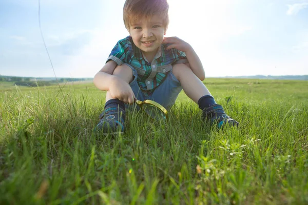 Молодий білий хлопчик вивчає сад в літній час зі своїм збільшувачем . — стокове фото