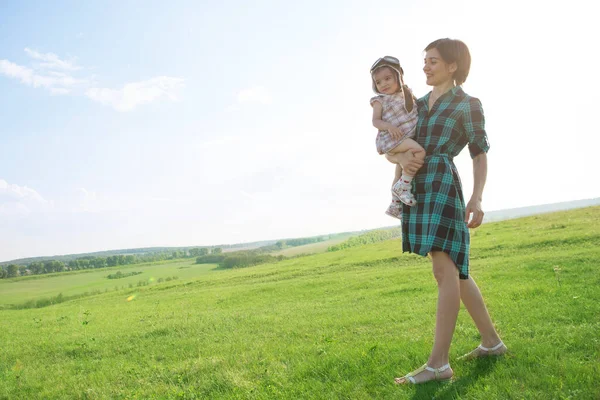 A beautiful mother with a cute daughter is playin on green field — Stock Photo, Image