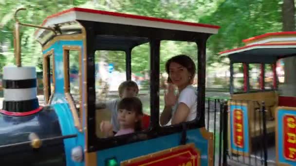 Mamma och barn kör ett litet ånglok. Familjekul i nöjesparken — Stockvideo