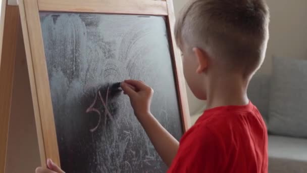 Το αγοράκι γράφει μαθηματικές εξισώσεις στον πίνακα και τις λύνει. — Αρχείο Βίντεο