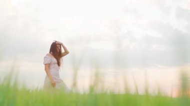 Buğday tarlasında gün batımında beyaz elbiseli bir kız.