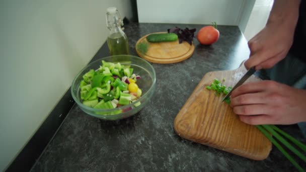 Man tillagar sallad i köket på ett svart bord — Stockvideo