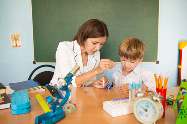 Teacher helping young boy with writing lesson. Back to school concept