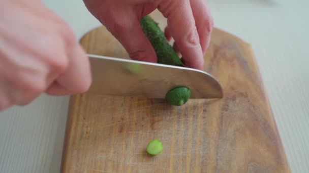 Manliga händer skär en gurka på en skärbräda — Stockvideo