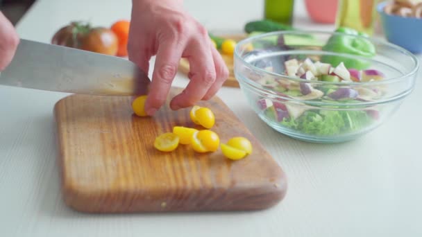 Manliga händer skär små gula körsbärstomater på en skärbräda — Stockvideo