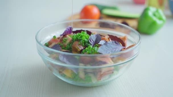 Оливковое масло наливают в миску овощного салата — стоковое видео