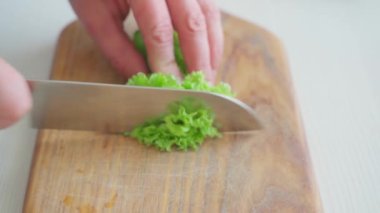 Erkek eller kesme tahtasıyla salata kesiyor.