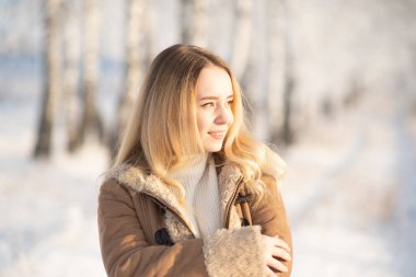 Beautiful girl in a frosty winter forest on a sunny day