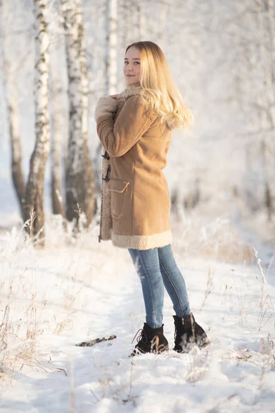 Beautiful girl in a frosty winter forest on a sunny day — Stockfoto
