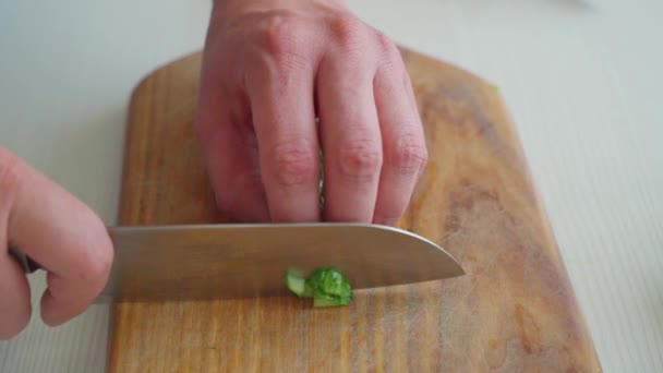 Mužské ruce krájejí okurku na prkně. — Stock video