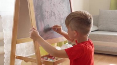 Küçük çocuk tahtaya matematik denklemleri yazar ve onları çözer.