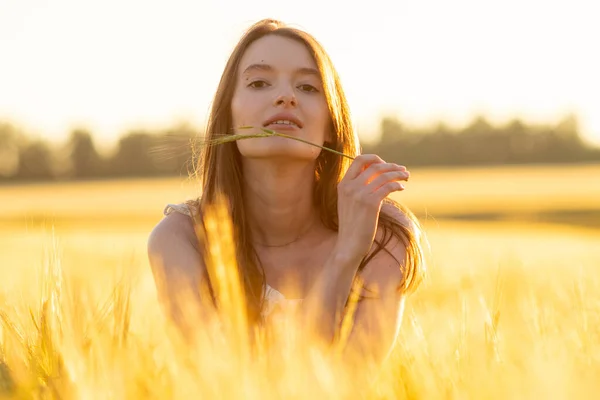 Dziewczyna w sukience w polu pszenicy o zachodzie słońca — Zdjęcie stockowe