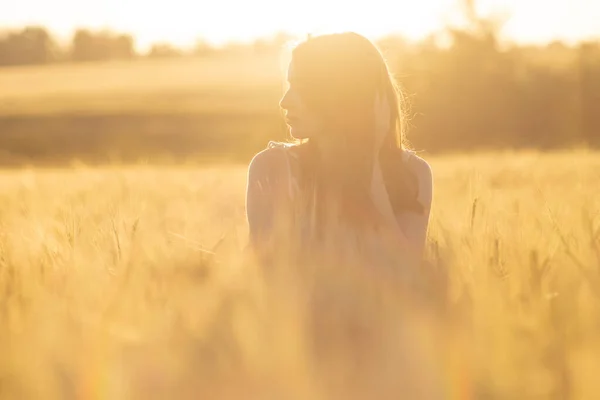 Dívka v šatech v pšeničném poli při západu slunce — Stock fotografie