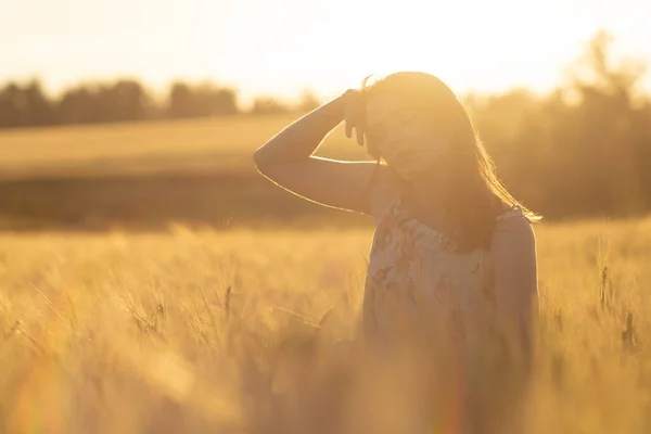 Chica en un vestido en un campo de trigo al atardecer — Foto de Stock