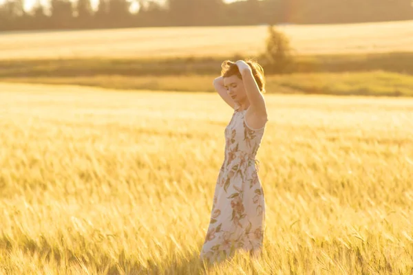 Mädchen in einem Kleid in einem Weizenfeld bei Sonnenuntergang — Stockfoto