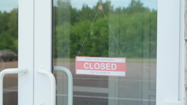 Чоловік змінює знак CLOSED на знак OPEN. Інформаційна пластина на прозорих дверях або на складі під час пандемії COVID-19. — стокове відео