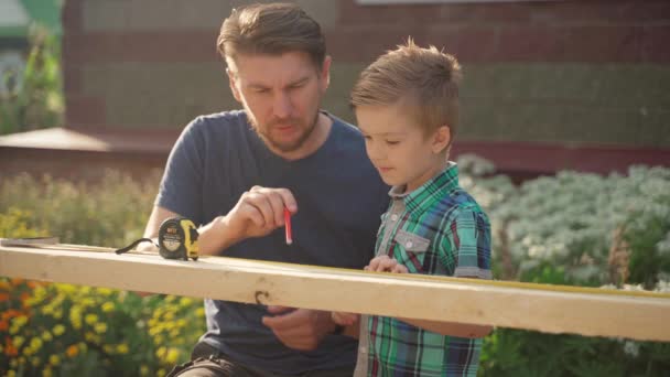 Menuisier avec son fils travaillant à l'extérieur près de la maison — Video