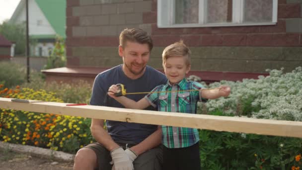 Menuisier avec son fils travaillant à l'extérieur près de la maison — Video