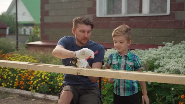Man snickare med sin son arbetar utanför nära huset — Stockvideo