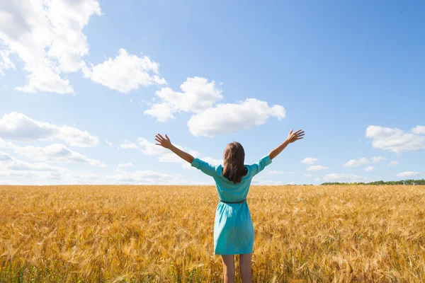 Young woman enjoying sunlight with raised arms in straw field — Stock Photo, Image