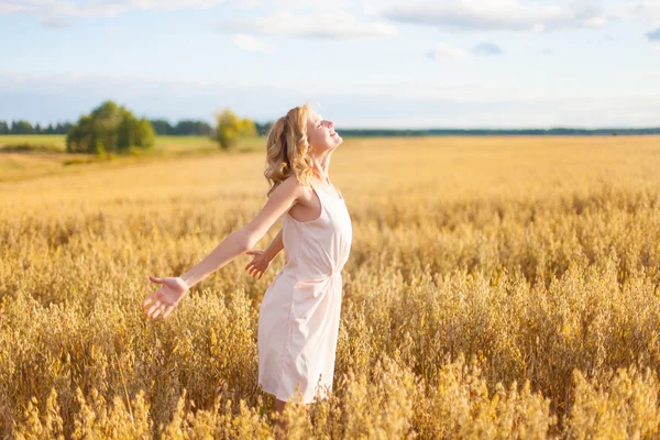 Donna che alza le braccia godendo la luce del sole nel campo — Foto Stock