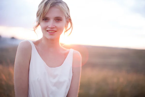 Hübsche junge Frau auf der Sommerwiese bei gelbem Sonnenuntergang — Stockfoto
