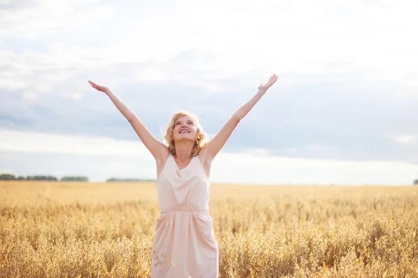 Frau hebt Arme und genießt Sonnenlicht auf Feld — Stockfoto