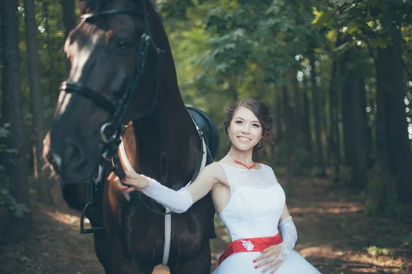Mladá žena v bílých šatech, stojící s koněm — Stock fotografie