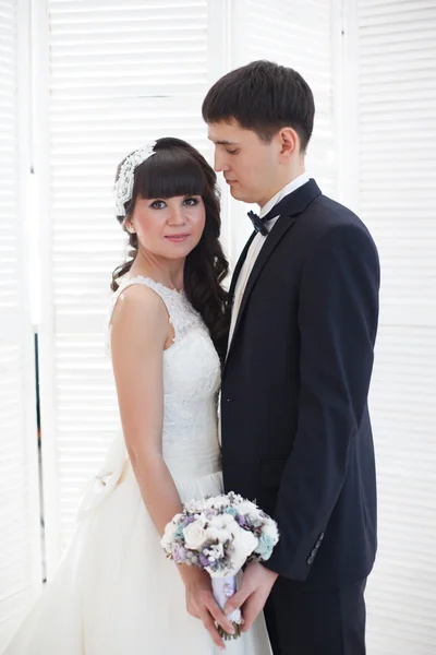 Recém-casados no fundo de uma parede branca . — Fotografia de Stock