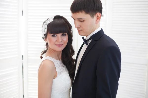 Recién casados en el fondo de una pared blanca . — Foto de Stock