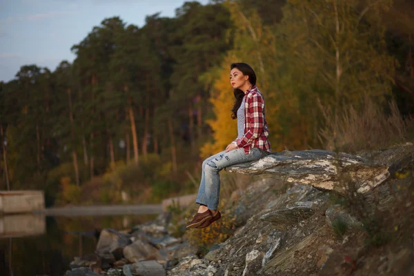 Frau sitzt auf Stein von Sonnenuntergang und Meer oder See — Stockfoto