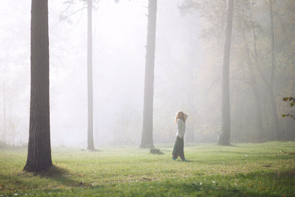 Young girl dancing in the forest. Sun rays beating down on woman walking in forest