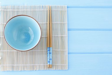 suşi ve sopalarla temiz mavi bir tablo için kase