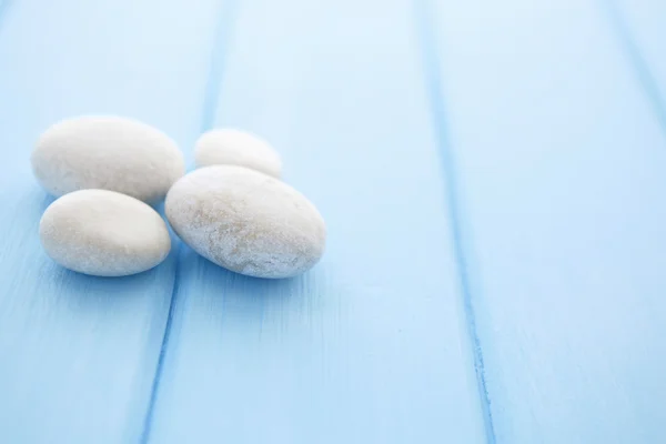 Haufen weißer Steine auf einem blauen Holztisch — Stockfoto