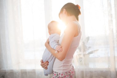 Onun annesi oturma odası kollarında küçük bebek.