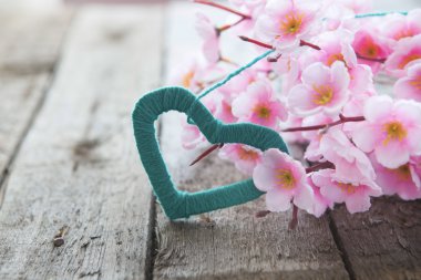 Ahşap yüzeyde narin pembe çiçekli çiçekli dal. 