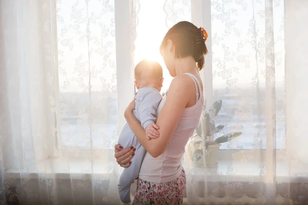 Mãe amorosa brincando com seu bebê na janela — Fotografia de Stock