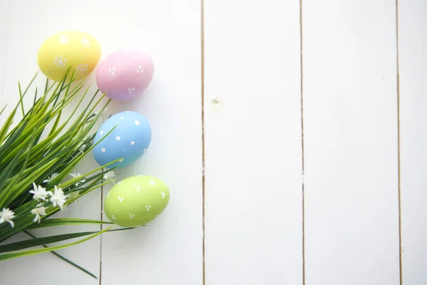 Renkli Paskalya yumurta beyaz ahşap zemin üzerine dekore edilmiştir.. — Stok fotoğraf